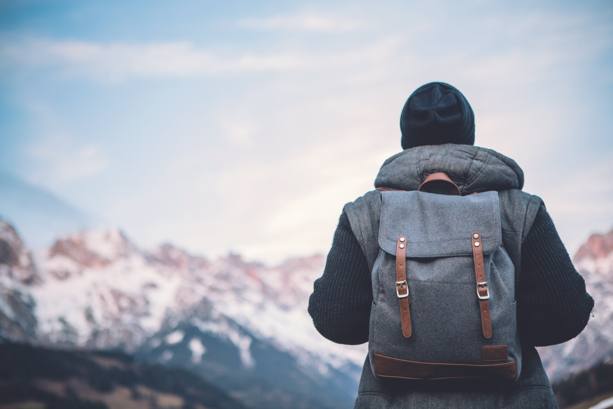 Person mit Rucksack steht vor den Bergen.